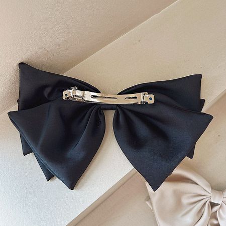 Detail view of the sturdy silver French clip on the back of a black bow.