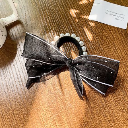 Close-up of a black elastic hair tie with an elegant decorative bow.