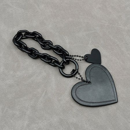 Detailed view of the black heart-shaped bag charm showcasing its texture and metal chain.