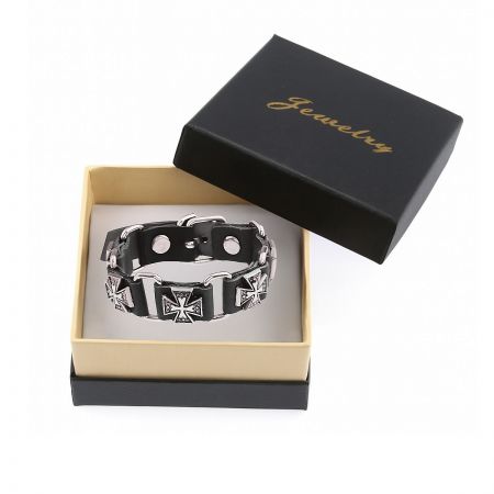 The black cross leather bracelet presented in a jewelry box.