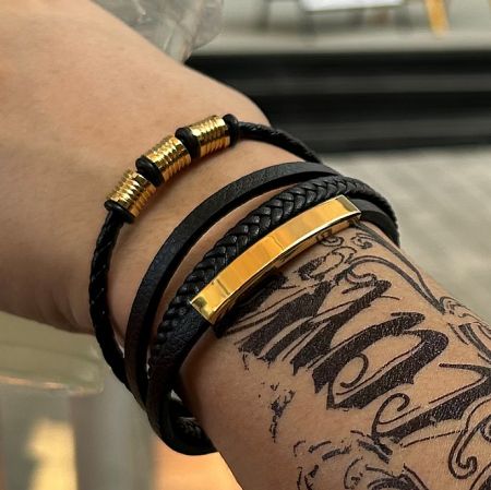 A collection of black PU leather bracelets with elegant gold-plated accents, showcasing different styles.