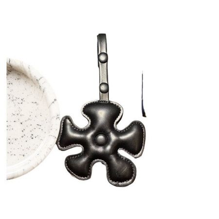 Close-up of the black four-leaf clover leather charm, highlighting its texture.