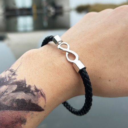 A man wearing the black braided PU leather bracelet with infinity clasp, showing how it looks on the wrist.