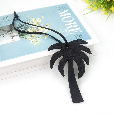 Close-up of the black coconut tree leather keychain, showing its detailed shape and texture.