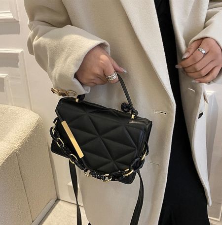 Quilted PU Leather Handbag - A woman in a stylish outfit holding the elegant black quilted PU leather handbag with a gold chain strap from JR Fashion Accessories.