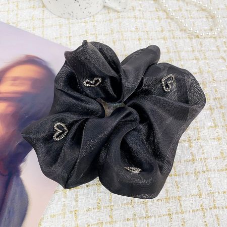 A stylish black scrunchie made from shiny fabric with silver heart embellishments.