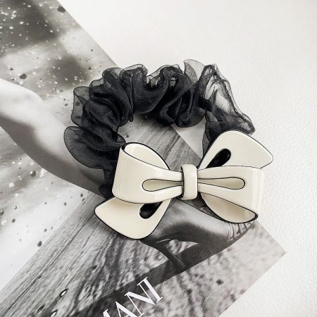 A stylish black scrunchie paired with a classic white acetate bow clip.