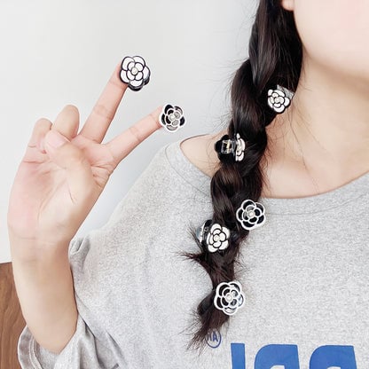A black camellia flower hair clip elegantly styled in a hair braid.