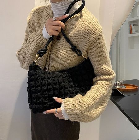 A model holding the black textured cloudy pattern handbag, showcasing its style and size