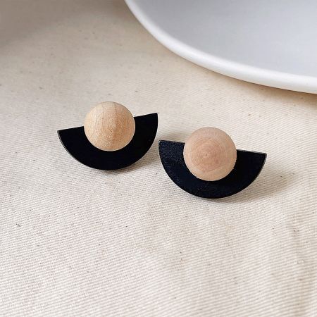 A detailed product shot of the black and wood fan-shaped earrings, highlighting their texture and design.