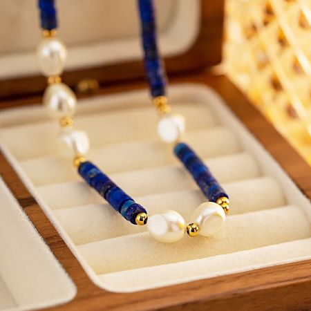 The blue and white beaded necklace presented beautifully in a wooden jewelry box.