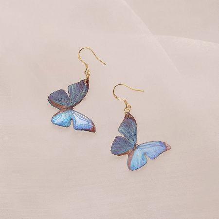 Detailed view of the blue butterfly earring with gold hook.