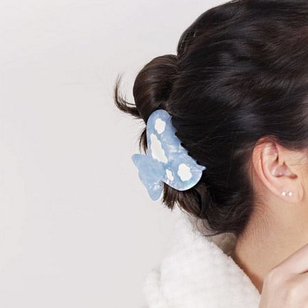 A model wearing a blue butterfly-shaped acetate hair clip with white spots.