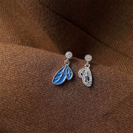 Studio shot of the asymmetrical earring pair, highlighting the blue leaf and crystal-encrusted leaf designs.
