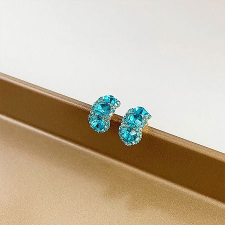 A detailed view of the gold stud earrings with vibrant blue gemstones.