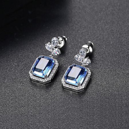 Detailed shot of the blue gemstone earrings highlighting the floral accent and surrounding white stones.