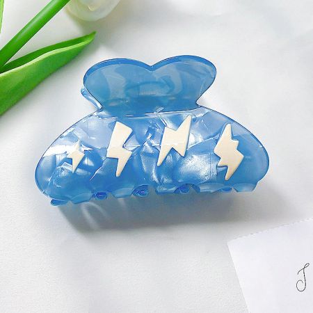Close-up of a blue acetate hair clip featuring a white lightning bolt design.