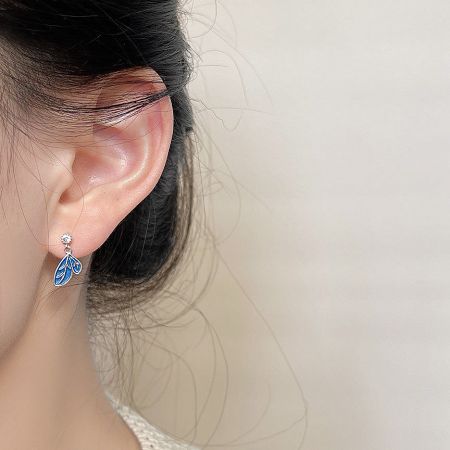 Close-up of the blue enamel leaf earring being worn to show scale and style.