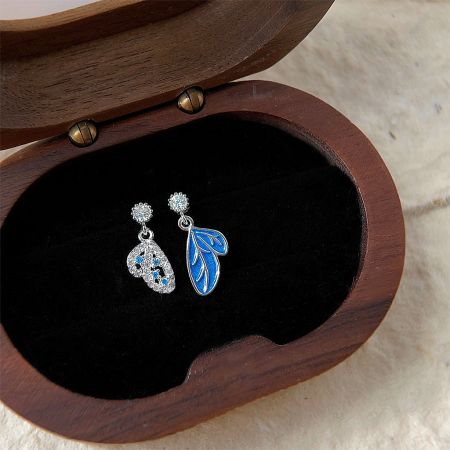 Silver Plated Blue Enamel Zircon Asymmetrical Butterfly Drop Earrings (5 Pairs) - A pair of silver-plated asymmetrical butterfly drop earrings with blue enamel and zircon, elegantly displayed in a wooden jewelry box.