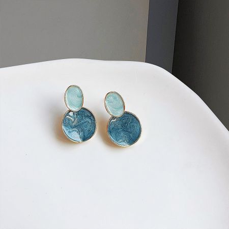 A close-up of the unique marbled blue and white design of the earrings.