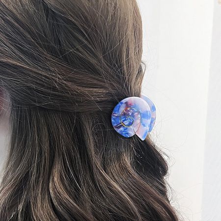 A blue marbled conch shell hair clip securing a section of hair.