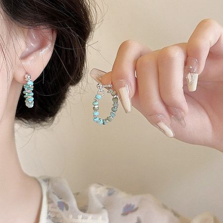 Close-up of a silver hoop earring with blue and silver beads.