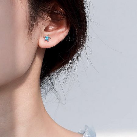 Close-up of the blue enamel starfish earring being worn, showcasing its size and vibrant color.