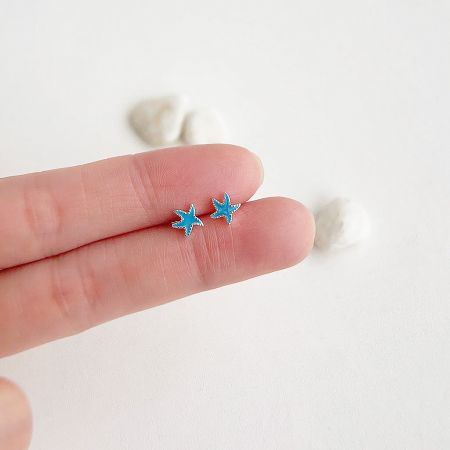A pair of the small, blue star-shaped earrings displayed together.