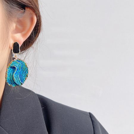 A model wearing a stylish Klein blue starry-sky texture earring, showcasing its dangle design.