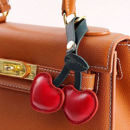 PU Leather Red Cherry Bag Charms (5 pcs) - A stylish brown leather handbag adorned with a cute red cherry-shaped PU leather bag charm, showcasing its use as a fashion accessory.