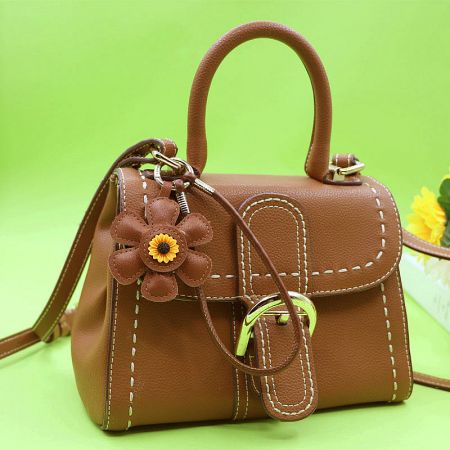 Sunflower keychain attached to a brown leather purse as a bag charm.