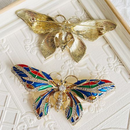 A pair of butterfly brooches showing different color variations and stone arrangements.
