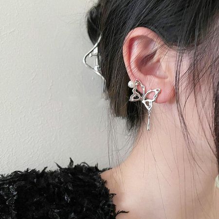 A sterling silver butterfly earring shown on a model's ear, highlighting its punk-inspired design.
