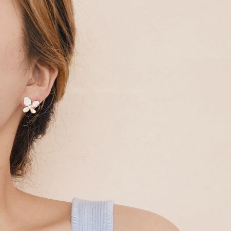 Close-up view of the white enamel butterfly earring being worn, showcasing its delicate design.