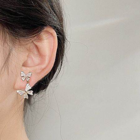 Model showcasing the elegant white enamel butterfly drop earrings.