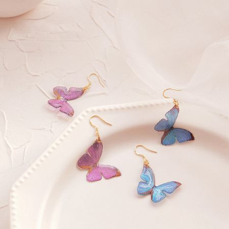 Lightweight Colors Butterfly Dangle Hook Earrings (Set of 5 Pairs) - A set of lightweight brass butterfly dangle earrings shown in vibrant purple and blue glittery finishes, with gold-tone hooks.