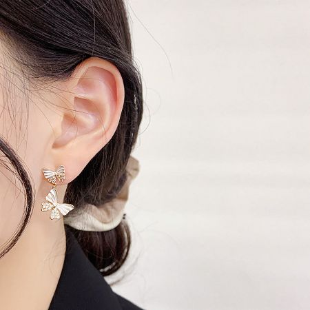 Side profile of a model wearing the gold and white butterfly statement earrings.