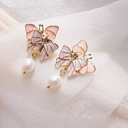 Close-up view of the double butterfly earrings highlighting the enamel details and pearl drops.