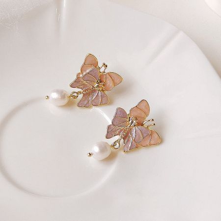 A pair of butterfly earrings with lustrous pearl accents, displayed to show their intricate design.