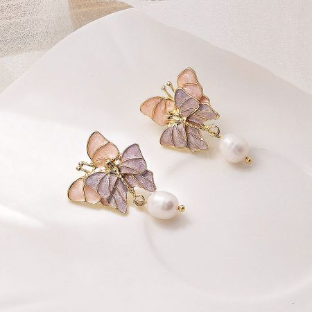 Detailed shot of the butterfly earrings featuring pink and purple stone wings and white pearls.