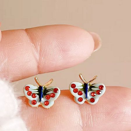 A pair of butterfly earrings with red dot details on the wings.
