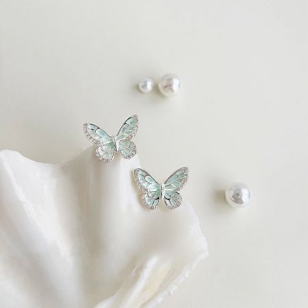 Wholesale Silver Plated Mint Green Enamel Butterfly Stud Earrings (5 pairs) - A pair of wholesale silver-plated butterfly stud earrings with mint-green enamel and clear rhinestones, elegantly displayed on a white seashell.