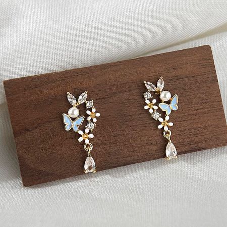 Full view of the butterfly and floral earrings, showing the combination of blue enamel, pearls, and crystals.