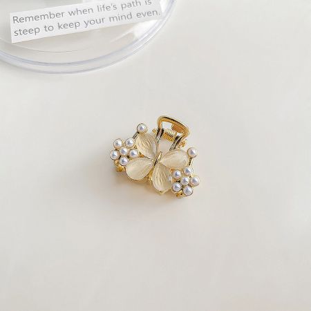 Detailed view of a butterfly-shaped mini hair claw clip adorned with lustrous pearls and a central stone.