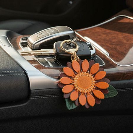 A vibrant leather sunflower keychain attached to car keys, demonstrating its use as a car accessory.