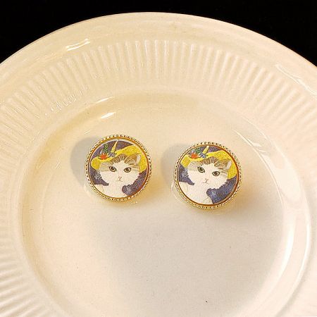 A pair of the cat painting stud earrings displayed elegantly on a decorative plate.