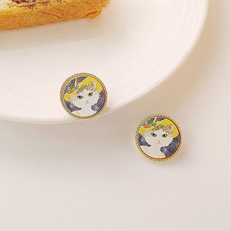 Close-up view of the brass cat-themed stud earrings with gold frames.
