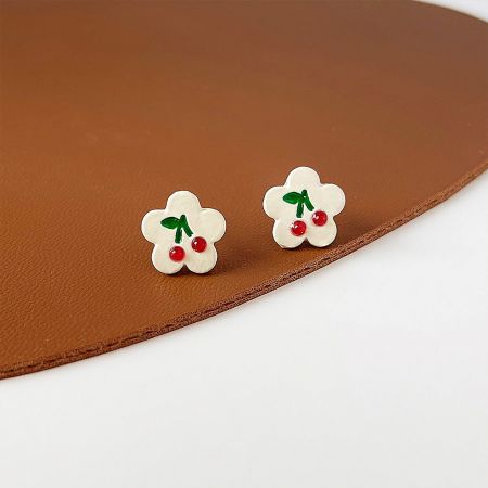 Close-up detail of the cherry-themed flower earrings showcasing the enamel work.