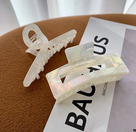 A pair of transparent acetate hair claw clips shown against a neutral background.