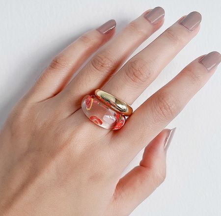 A model's hand wearing the clear resin ring with fruit accents, showcasing its unique and playful style.